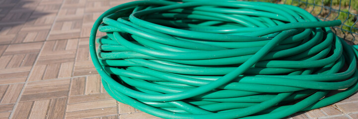 Bundle of garden hose on lawn in summer garden