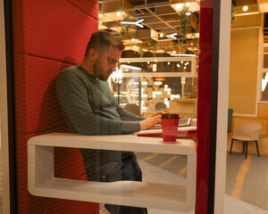 A bearded man in a booth for online negotiations. Privacy booth.