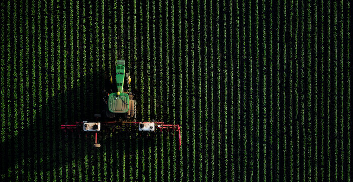 Tractor John Deere and rotary cultivator fights weeds the field with the use of chemicals to protect the plants. A top view of the field treatment. 07.07.22, Rostov region, Russia.