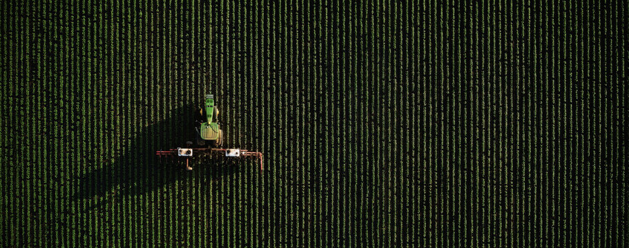 Tractor John Deere and rotary cultivator fights weeds the field with the use of chemicals to protect the plants. A top view of the field treatment. 07.07.22, Rostov region, Russia.