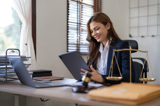 Attractive young lawyer in office Business woman and lawyers discussing contract papers with brass scale on wooden desk in office. Law, legal services, advice, Justice and real estate concept