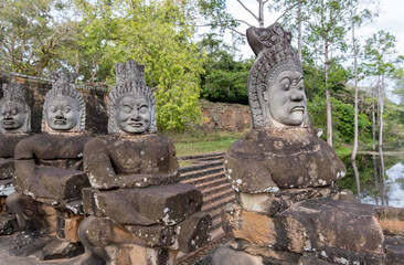 Old and new faces of the Buddha on the bridge near the exit from Angkor Bat. Siem Reap, Cambodia