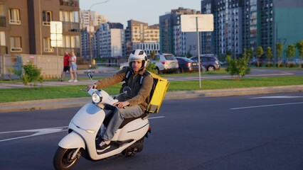 Grocery delivery in the city. A man on a scooter rides on the road