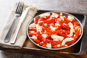 Esgarraet Cod salad with grilled red peppers, garlic and olive oil closeup on the plate on the wooden board. Horizontal
