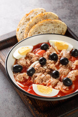 Murcian Salad La ensalada murciana with tomato, canned tuna, black olive, egg and onion closeup on the plate on the wooden board. Vertical
