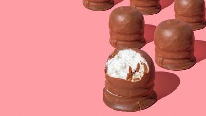 Israeli winter dessert Krembo (chocolate covered marshmallow fluff) on pink background with copy space.