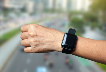 hand wearing smart watch on blurred city background. wearable gadget concept