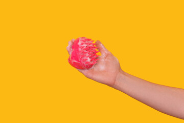 Scalp massager pink color female hand against yellow background.
