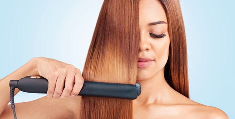 Face, beauty and woman with hair straightener in studio isolated on a blue background. Haircare,...