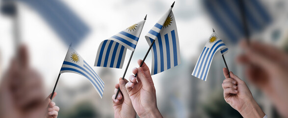 A group of people holding small flags of the Uruguay in their hands