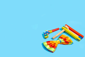 Clown bow tie, colorful noisemakers for Jewish holiday Purim on blue background with copy space.