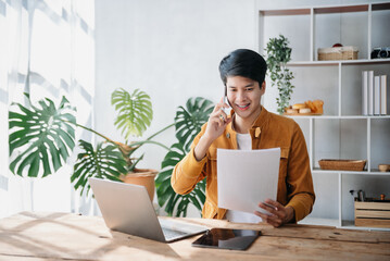 Portrait of young Asian man sitting at his desk in the office