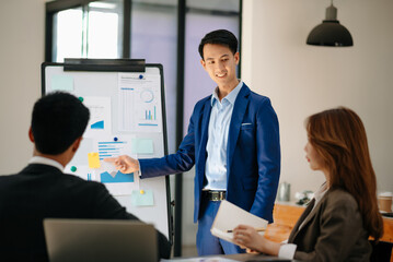 Male entrepreneur smiling while delivering a presentation to team in office boardroom. Businesswoman having meeting with colleagues with coworkers in office..