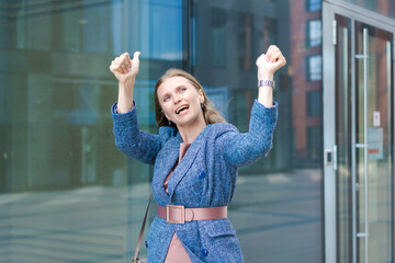 Happy business woman showing thumbs up while standing outdoors against office building background in summer wearing business clothes winner and successful deal friendly smiling, Recommendation concept