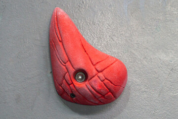 Red climbing holds on the grey climbing wall close-up