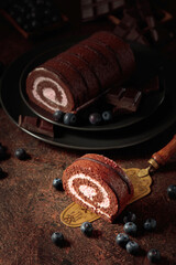 Chocolate roll cake with blueberries and a broken chocolate bar.