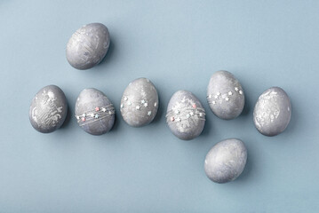 Festive Easter background. Gray-blue Easter eggs with stars on a blue table. Greeting card. Top view.