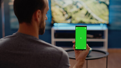 Person with modern smartphone looking at green screen vertical background in living room. Caucasian...