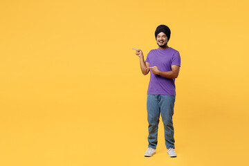 Full body smiling devotee Sikh Indian man ties his traditional turban dastar wear purple t-shirt...