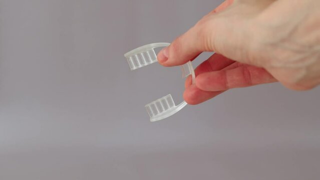 Nighttime dental care. Keeping teeth healthy overnight. Mouth guard in a woman's hand on a beige background