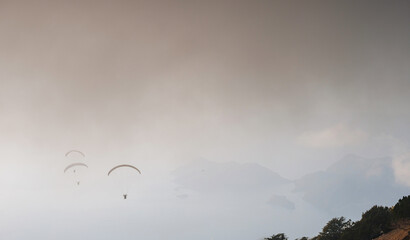 Paragliding in sky. Paraglider tandem flying over sea and mountains