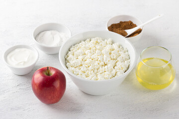Ingredients for low-calorie cottage cheese casserole with apple: cottage cheese, apple, egg white, rice flour, sour cream, brown sugar on a light gray background