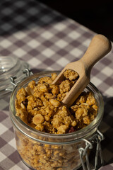 Homemade granola with nuts and seeds in eco glass jar. Healthy snack on breakfast. Muesli from oatmeal, raisins, honey, cranberry, flax, almond, cashew, freshly baked
