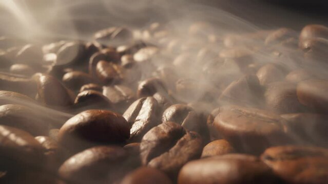 Process of roasting coffee beans. Smoke comes from fresh coffee seeds.Sliding shot of roast coffee beans with smoke on dark background