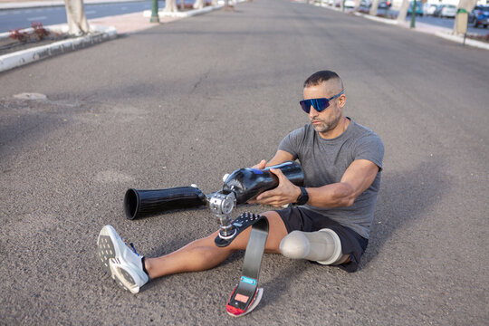 Male amputee putting on artificial leg before running outdoors