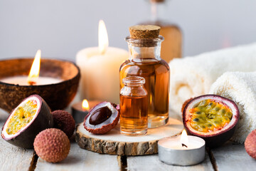 Glass bottles with pure organic essential litchi and passion fruit oil on wooden background. Concept of natural ingredients for beauty treatment, skin care, massage. Exotic fruits extract and essence