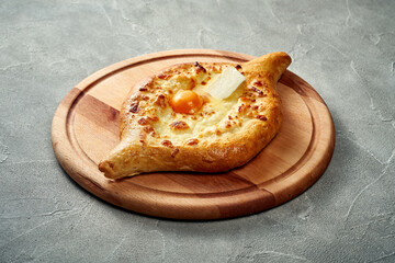 Khachapuri with salty melted cheese and egg yolk in a plate. Concrete background