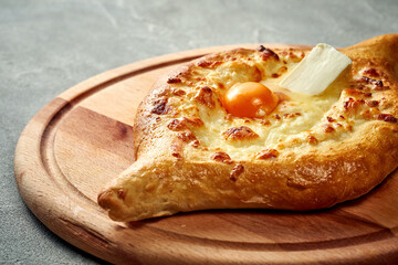 Khachapuri with salty melted cheese and egg yolk in a plate. Concrete background