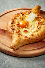 Khachapuri with salty melted cheese and egg yolk in a plate. Concrete background