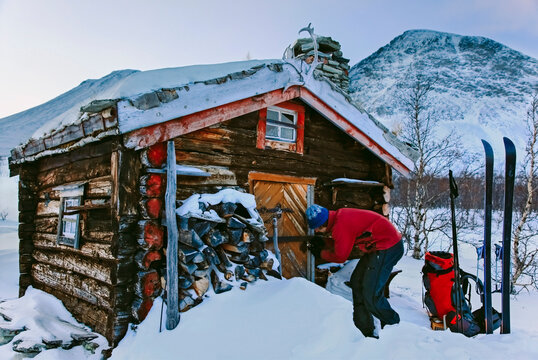Skier opening log cabin, Rondane National Park, Oppland County, Norway