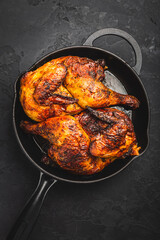 Roasted half chicken in pan on black background