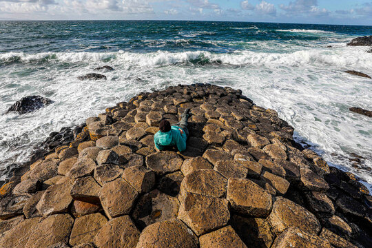 Woman enjoys the waves on Giant's causeway.