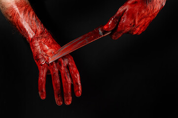 A man wipes a bloody knife with his hand on a black background.  © Михаил Решетников