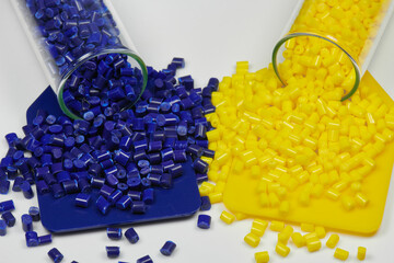 blue and yellow colored plastic resin granulate in glass test tubes