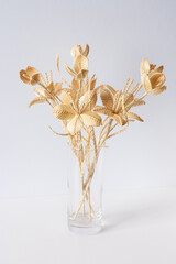 A glass vase with a bouquet of flowers made from straw on a white background