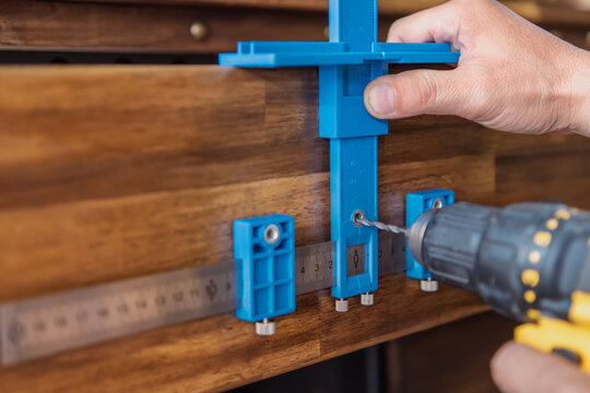 carpenter use a cabinet hardware jig adjustable punch locator drill guide sleeve for Install cabinet handles and knobs ,DIY maker and woodworking concept. selective focus