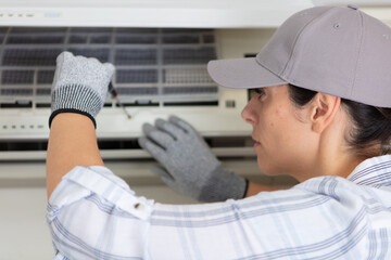 portrait of a young woman adjusting air conditioning system