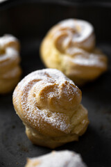 Decorating profiteroles with powdered sugar. Eclairs with icing sugar