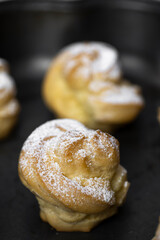 Decorating profiteroles with powdered sugar. Eclairs with icing sugar