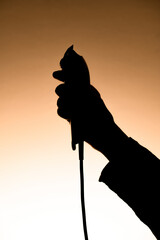 dark silhouette of male hand holding an electric hair clipper. - obrazy, fototapety, plakaty