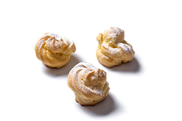 Decorating profiteroles with powdered sugar. Eclairs with icing sugar