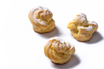 Decorating profiteroles with powdered sugar. Eclairs with icing sugar