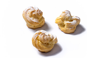 Decorating profiteroles with powdered sugar. Eclairs with icing sugar