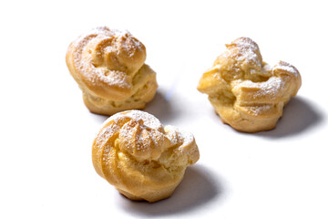 Decorating profiteroles with powdered sugar. Eclairs with icing sugar