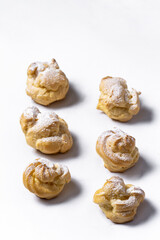 Decorating profiteroles with powdered sugar. Eclairs with icing sugar