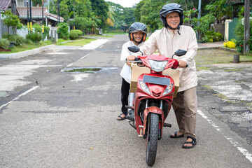 Asian Muslim family pushing a motorcycle when going mudik